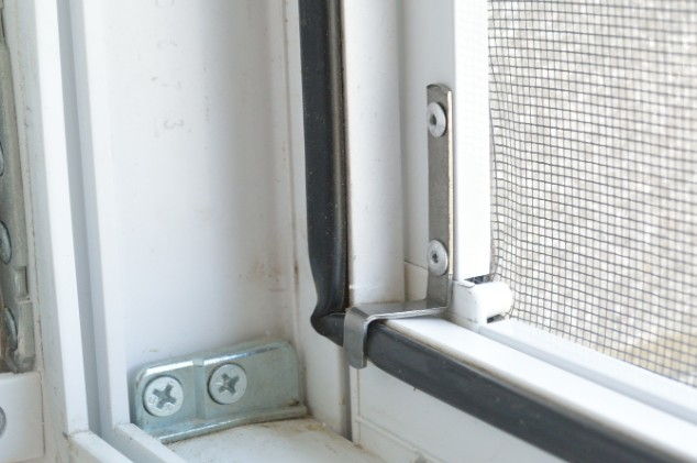 Escuadra metálica que sujeta el marco de una mosquitera al perfil de la ventana, pieza habitual en su reparación