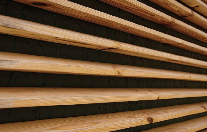 Lamas horizontales de madera de pino separadas entre sí, como en las persianas de madera tipo celosía