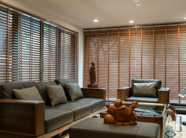 Salón con venecianas de madera de nogal a medida cubriendo dos ventanales de suelo a techo